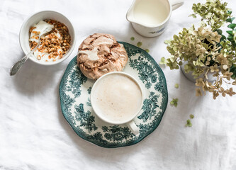 Cozy homemade breakfast - greek yogurt with granola, chocolate meringue, cappuccino on a light background, top view