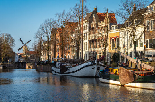 Old harbor of dutch city Schiedam, with historical windmill in the distance