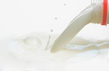 pouring milk to the surface from a plastic bottle on a white background