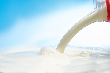 pouring milk to the surface from a plastic bottle on a blue background