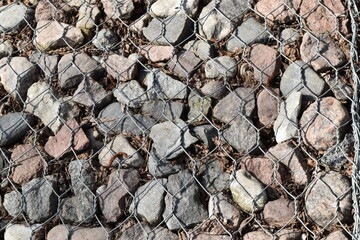 Background and texture, an accumulation of stones under a metal mesh.