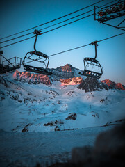 télésiège à l’arrêt à Tignes, en Savoie, avec la montagne au loin et le lever du soleil.