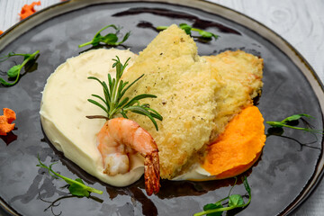 Top view of fish fillet in batter with mashed potato on wooden table