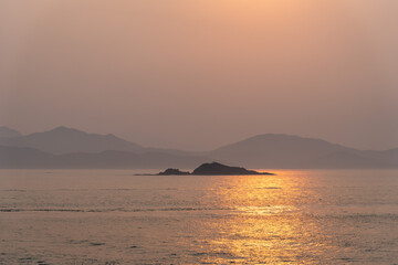 Naklejka na ściany i meble Beautiful sunrise above Chinese sea coast near Xiamen, foggy morning on golden hour.