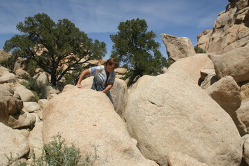 Woman Scrambling over Giant Boulders in Joshua Tree National Park, California, During a Hike