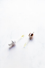 Retinol oil serum oil pipettes on isolated marble background. Beauty care concept.