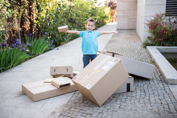 a little boy playing with the boxes he received in front of his house. Delivery