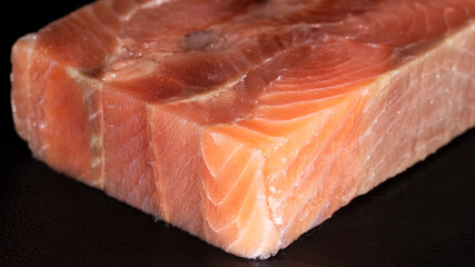 Cube piece of raw pink salmon fish on black background