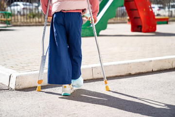 teen girl with a broken leg on crutches in the playground. 