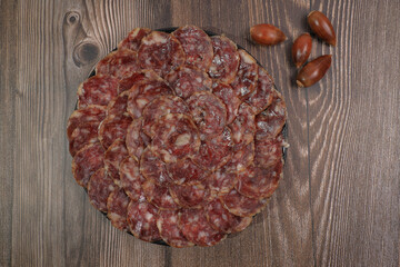 Ration of acorn-fed Iberian sausage 100% acorn in black plate decorated with acorns and wood background