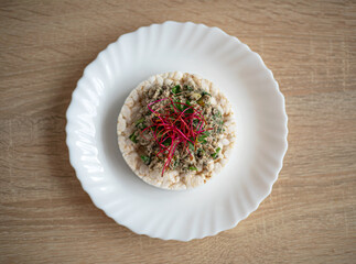 Healthy, tasty sandwich with rice waffle, fish paste, avocado and beetroot alfalfa sprouts on a white plate
