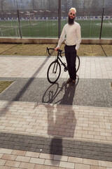 A young stylish businessman pushing a bicycle while going to work.