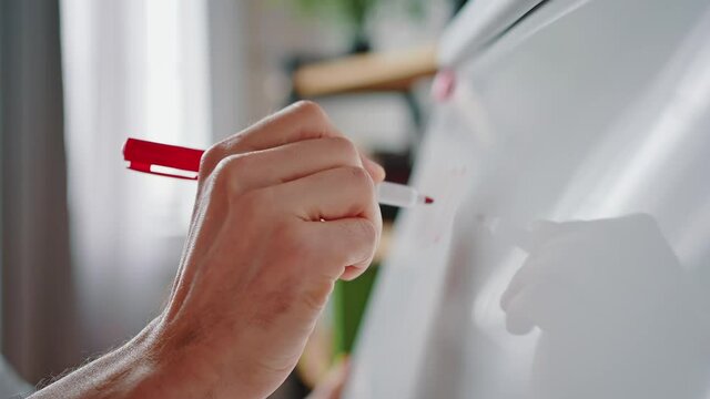 Confident teacher writing lesson theme on whiteboard, preparing for online session with students, tracking shot