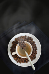 cup of steaming coffee with a spoon on a black napkin