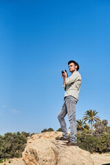 A male traveler takes photos on top of a rock