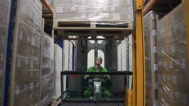 Warehouse male worker at forklift. loader unload goods from shelf and go down. concept logistics
