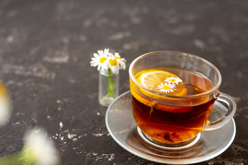 chamomile tea with lemon in a transparent cup on a black background. Breakfast concept, herbal tea.