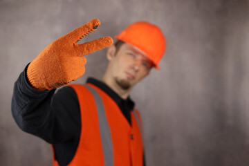 handsome man worker or engineer in helmet shows two finger gesture