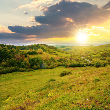 carpathian countryside in spring at sunset. beautiful rural landscape in mountain. wet grassy meadow in evening light. road winding through valley to village. distant ridge in the clouds