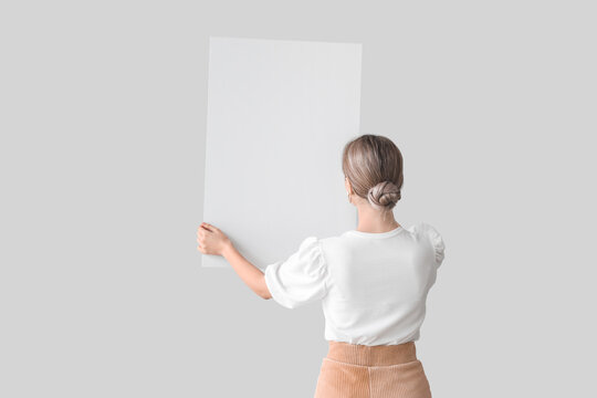 Beautiful Young Woman With Blank Poster On Light Background, Back View