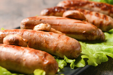 Plate with delicious grilled sausages on grunge background, closeup