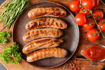 Plate with delicious grilled sausages on wooden background
