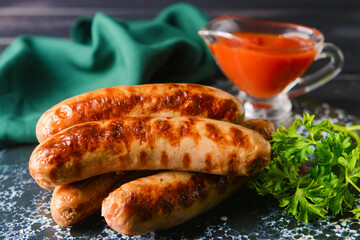 Delicious grilled sausages on dark wooden background