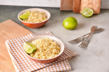 Bowls with tasty couscous and lime on table