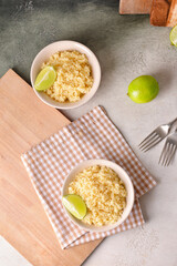 Bowls with tasty couscous and lime on table