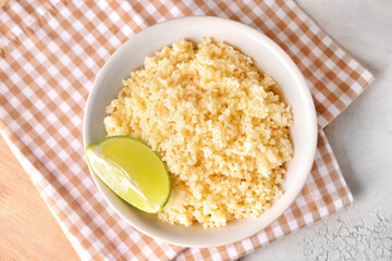 Bowl with tasty couscous and lime on table