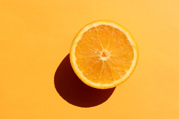 Half of orange on yellow background. Citrus fruit slice on colored backdrop. Top view, copy space....