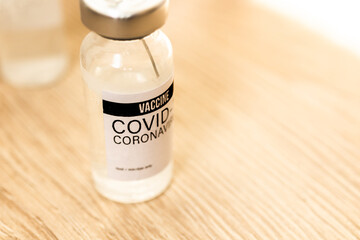 COVID-19 vaccine vial on the wooden table, preparing to the vaccination or immunization concept