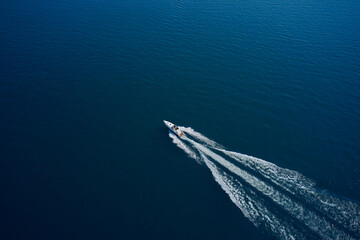 Top view of a white boat sailing to the blue sea. Drone view of a boat sailing. Aerial view luxury...