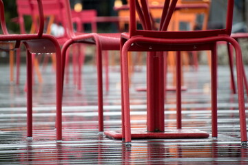 Red and orange furniture in street cafe on a wet deck