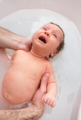 Fototapeta na wymiar small child takes a bath. Parents bathe the baby. Pretty Baby. The newborn is bathed. Crusts on the baby's face. Bathroom with milk. The newborn is smiling. Beautiful kid portrait. little child smiles