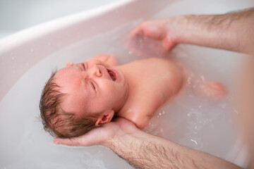 Fototapeta na wymiar small child takes a bath. Parents bathe the baby. Pretty Baby. The newborn is bathed. Crusts on the baby's face. Bathroom with milk. The newborn is smiling. Beautiful kid portrait. little child smiles