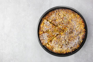 Almond homemade cake with sliced almonds topping and icing sugar on light concrete background. Top view. Copy space.
