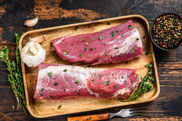 Marinated pork tenderloin meat steak with thyme. Dark wooden background. Top view