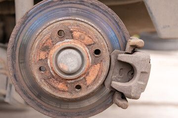 Heavily worn brake disc. Car brake disc after removing the wheel. A rusty disk that needs to be replaced.