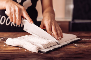 A girl slices a marshmallow cooked with her own hands on a beautiful wooden table, close-up in rustic style