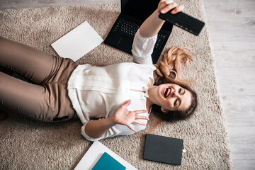 Business woman, girl with a laptop lying on a carpet on the floor in the living room at home.