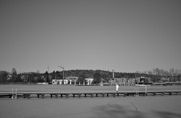 Lake Ukiel in Olsztyn in the winter time and a man dressed in white walking on the bridge