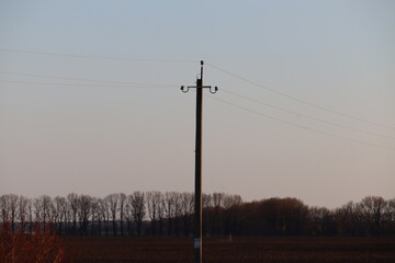 Fototapeta na wymiar Power transmission pole in the field. Spring.