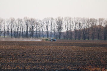 Tractor with a trailer on a plowed field. Agro theme.