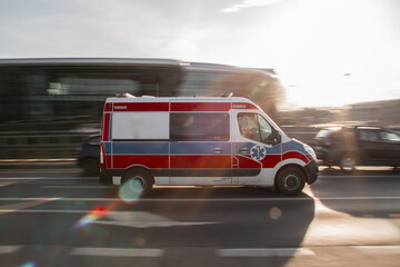 Fototapeta na wymiar An ambulance van responding near an intersection at sunset 