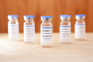 Vaccination covid-19 ampoules on brown background, coronavirus pandemic