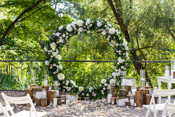 Newlyweds arch decorated in rustic style. Wedding decor with flowers, candles, succulents, greenery and wooden elements. Nature theme in wed ceremony decoration