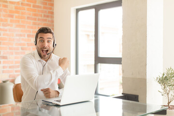 handsome telemarketer feeling happy, positive and successful, motivated when facing a challenge or...