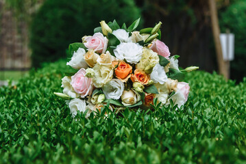 Wedding bouquet of roses close up among green bushes with blurred background