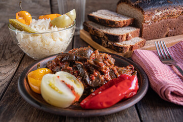 Sauerkraut, tomato, cucumber, and pepper in a glass bowl on a wooden table. Homemade pickles.
